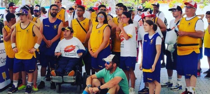 Grupo de jóvenes y adultos en camisetas de baloncesto, en un evento al aire libre.