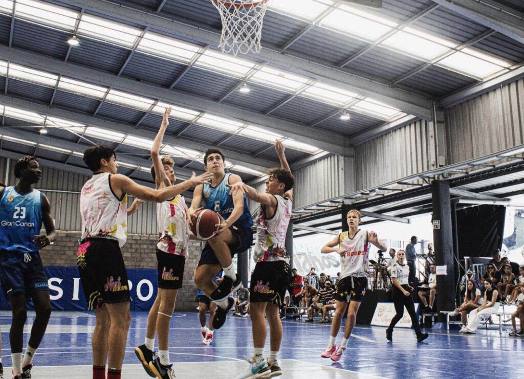Jugadores compiten por el balón en un partido de baloncesto en el torneo U16.