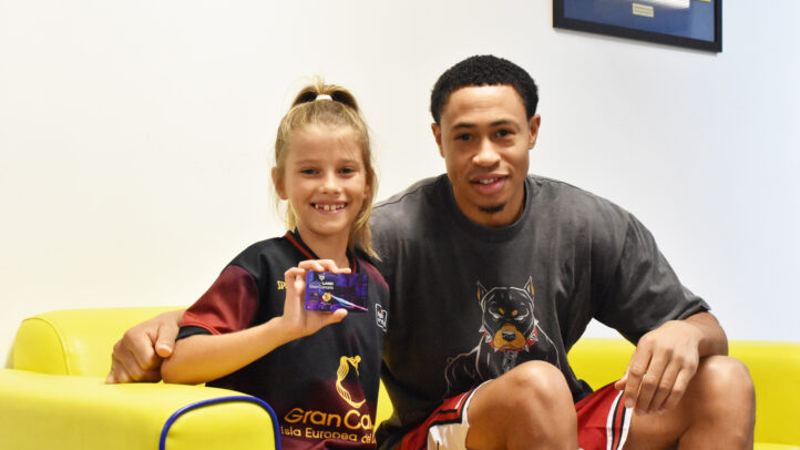 Niña sonriente con camiseta del club y jugador, sosteniendo un carné de abonado.