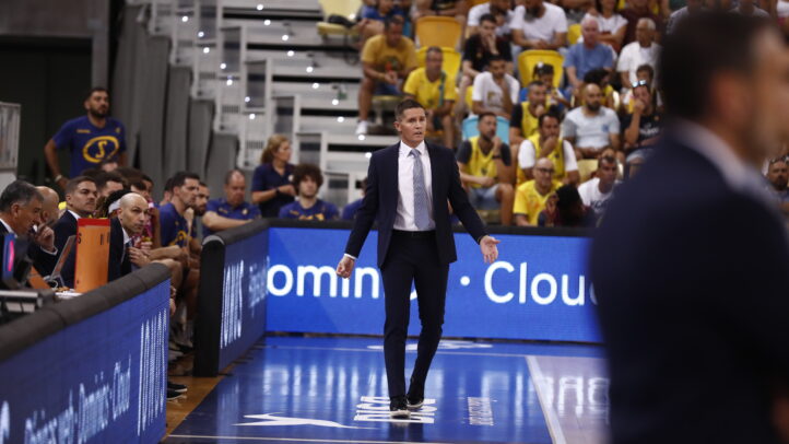 Entrenador Jaka Lakovic dirigiendo a su equipo durante un partido, con espectadores al fondo.