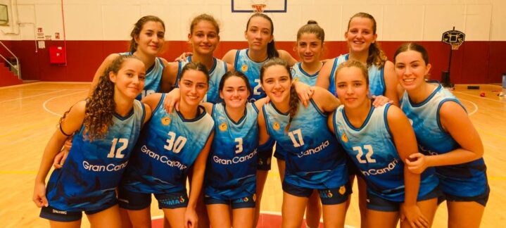 Equipo femenino de baloncesto de la cantera amarilla en el gimnasio, sonriendo.
