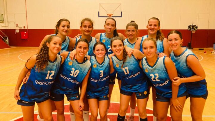 Equipo femenino de baloncesto de la cantera amarilla en el gimnasio, sonriendo.