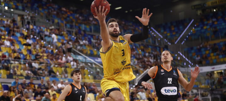 Jugador del Dreamland Gran Canaria lanza a canasta en un partido lleno de público.