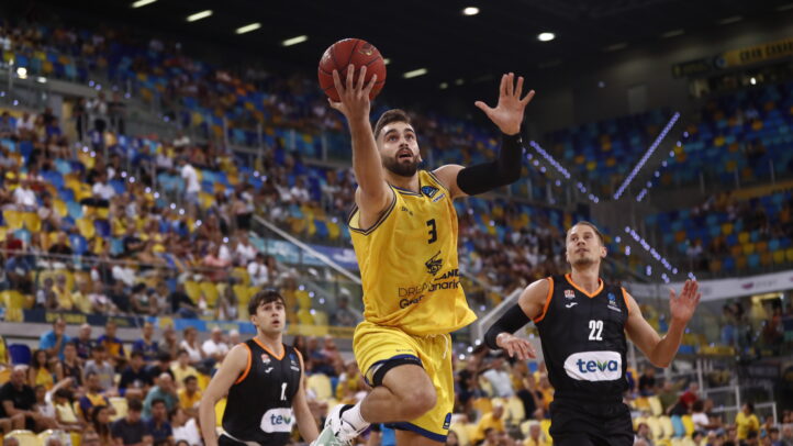 Jugador del Dreamland Gran Canaria lanza a canasta en un partido lleno de público.