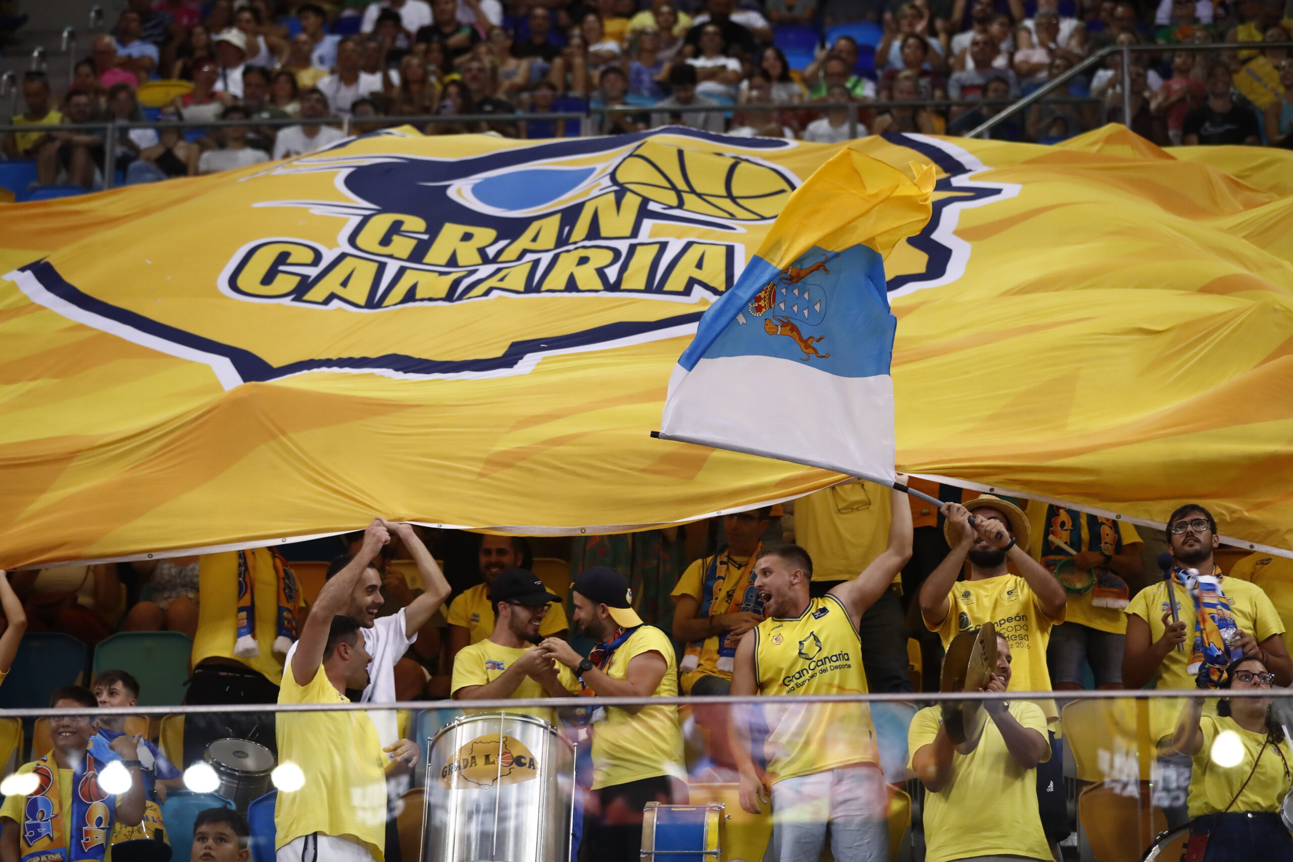 Aficionados del Club Baloncesto Gran Canaria animan con una gran bandera amarilla.