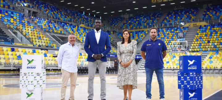 Cuatro personas posan en una cancha de baloncesto junto a cajas de la Fundación DISA.