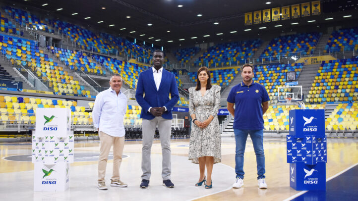 Cuatro personas posan en una cancha de baloncesto junto a cajas de la Fundación DISA.