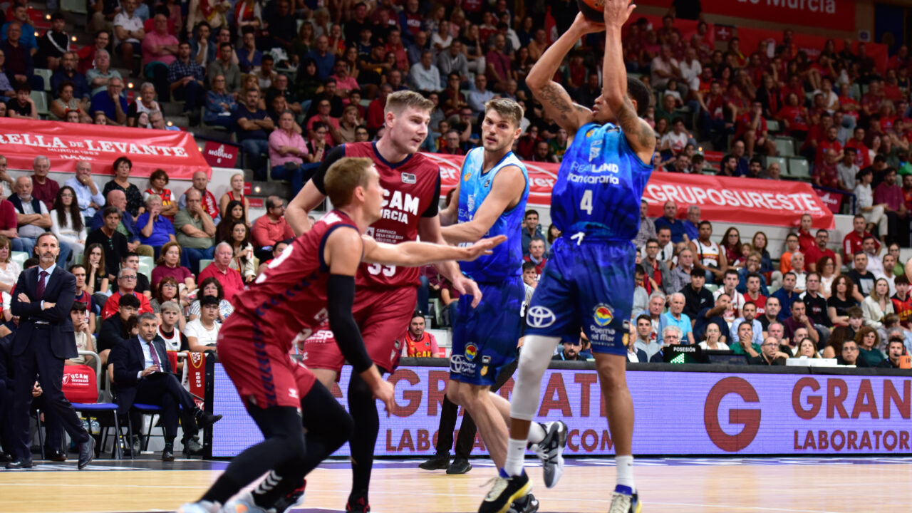 Baloncestista del Gran Canaria lanza a canasta ante defensores del equipo de Murcia.