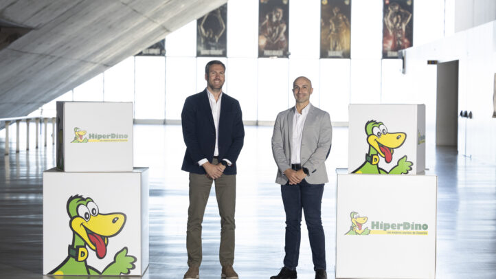 Dos hombres sonríen junto a cajas de HiperDino en un evento del Club Baloncesto Gran Canaria.