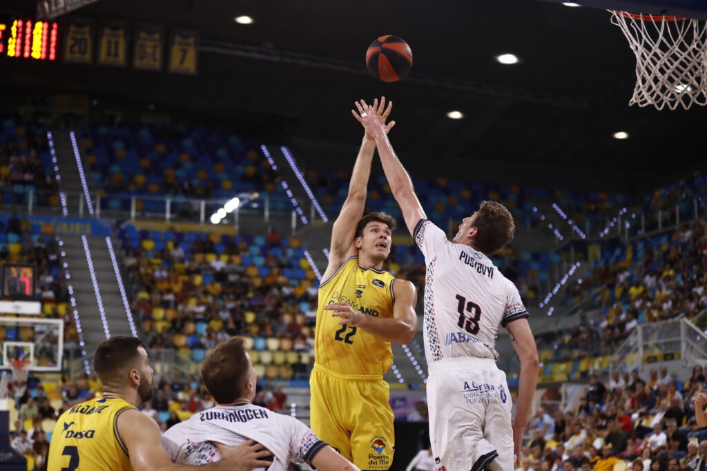 Jugador del Dreamland Gran Canaria lanza a canasta en un partido. Público de fondo.