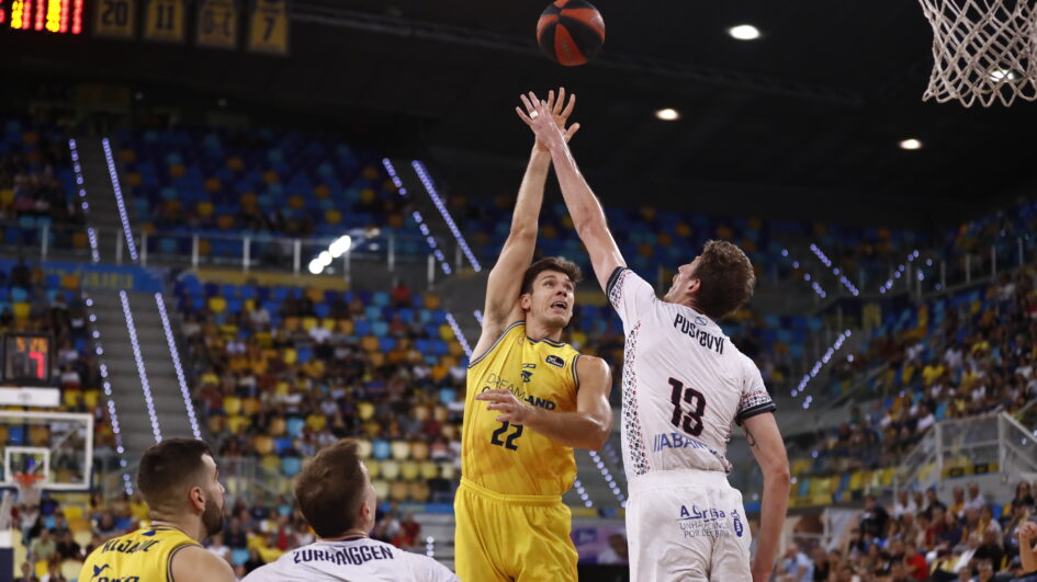 Jugador del Dreamland Gran Canaria lanza a canasta en un partido. Público de fondo.