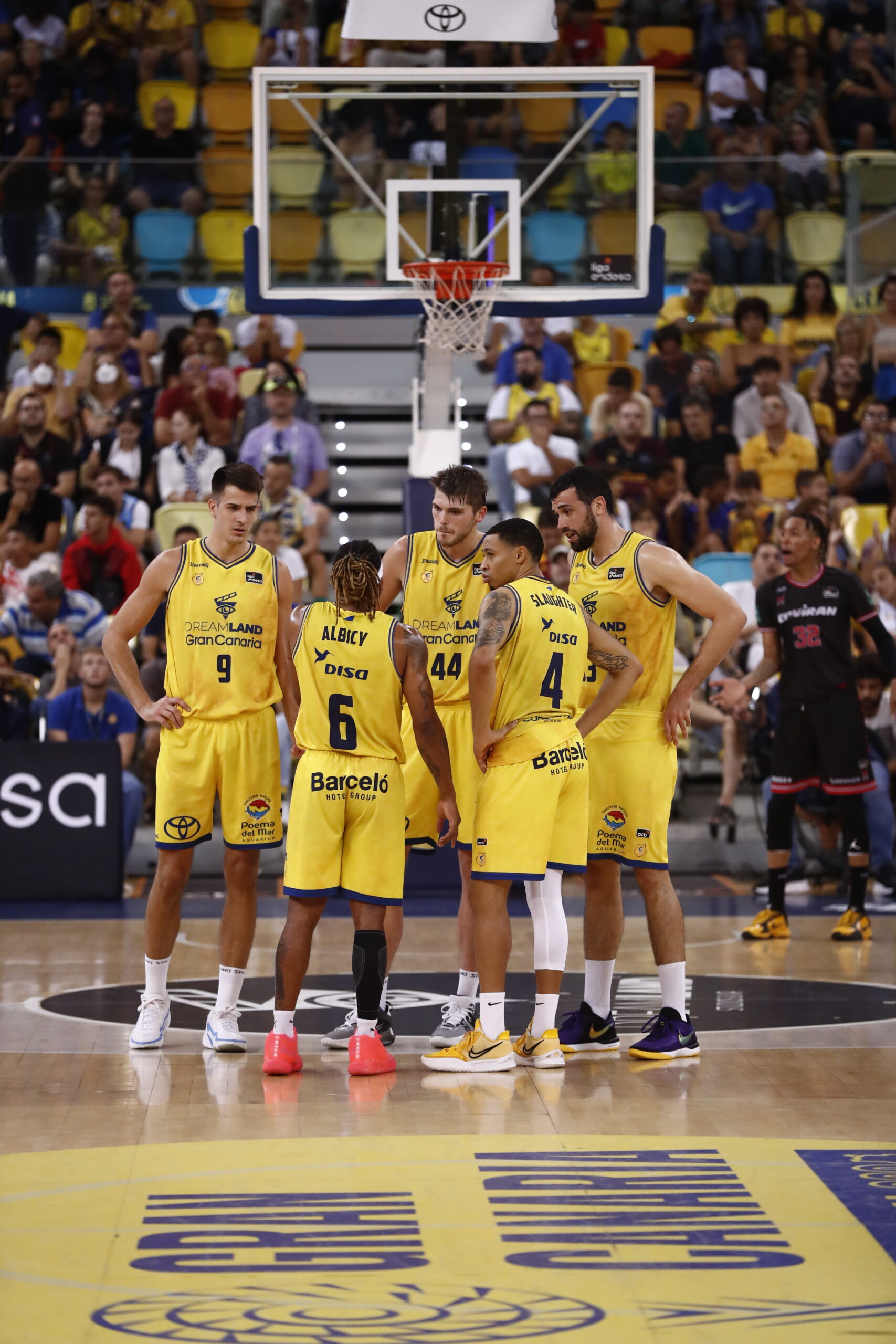 Jugadores del Gran Canaria en un tiempo muerto, discutiendo estrategias durante el derbi.