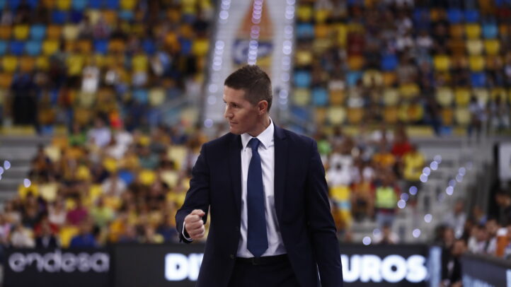 Entrenador Jaka Lakovic caminando por la pista durante un partido, con público al fondo.
