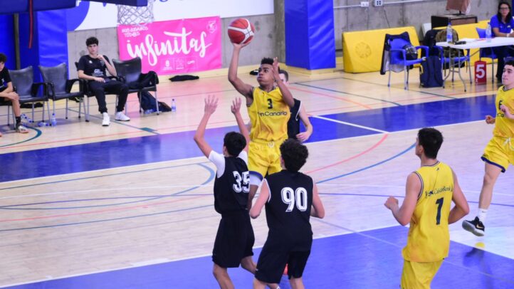 Jugador del CB Gran Canaria lanza a canasta mientras otros jugadores defienden.