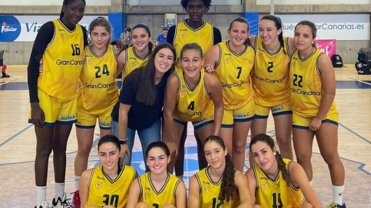 Equipo de baloncesto femenino posando juntos en la cancha tras un triunfo.