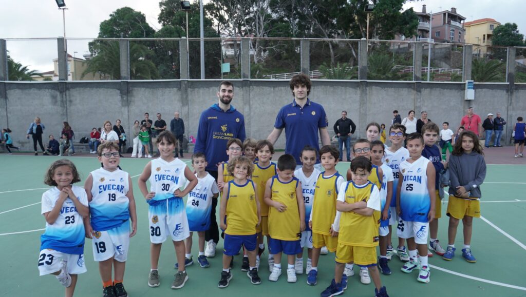Jugadores de baloncesto juvenil posando con un entrenador en la jornada inaugural de la liga.