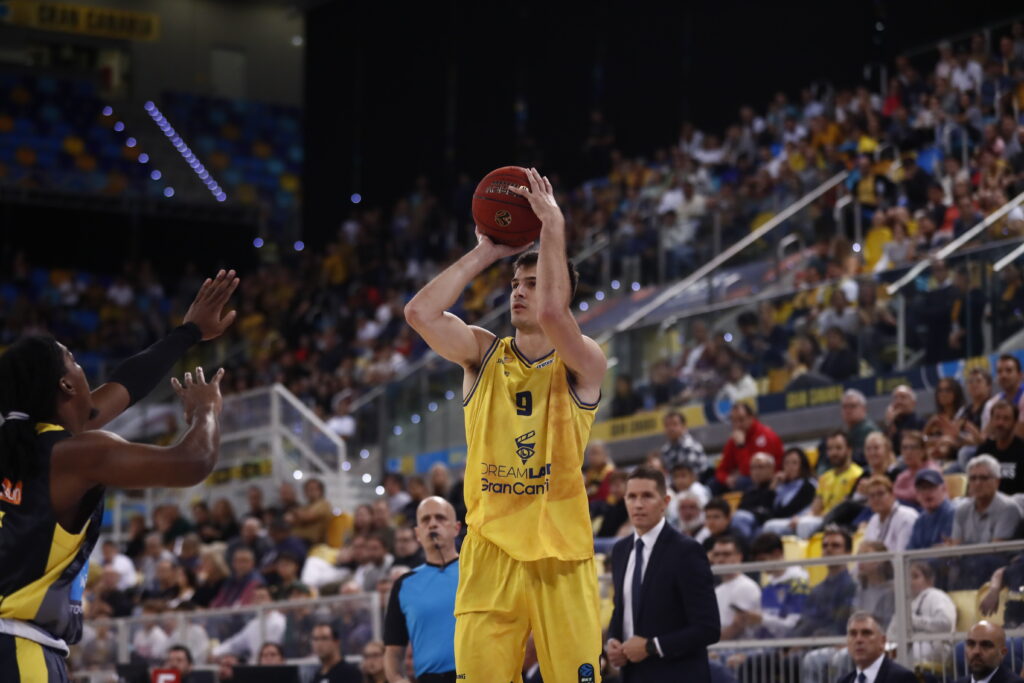 Jugador del CB Gran Canaria lanza a canasta durante un partido concurrido.
