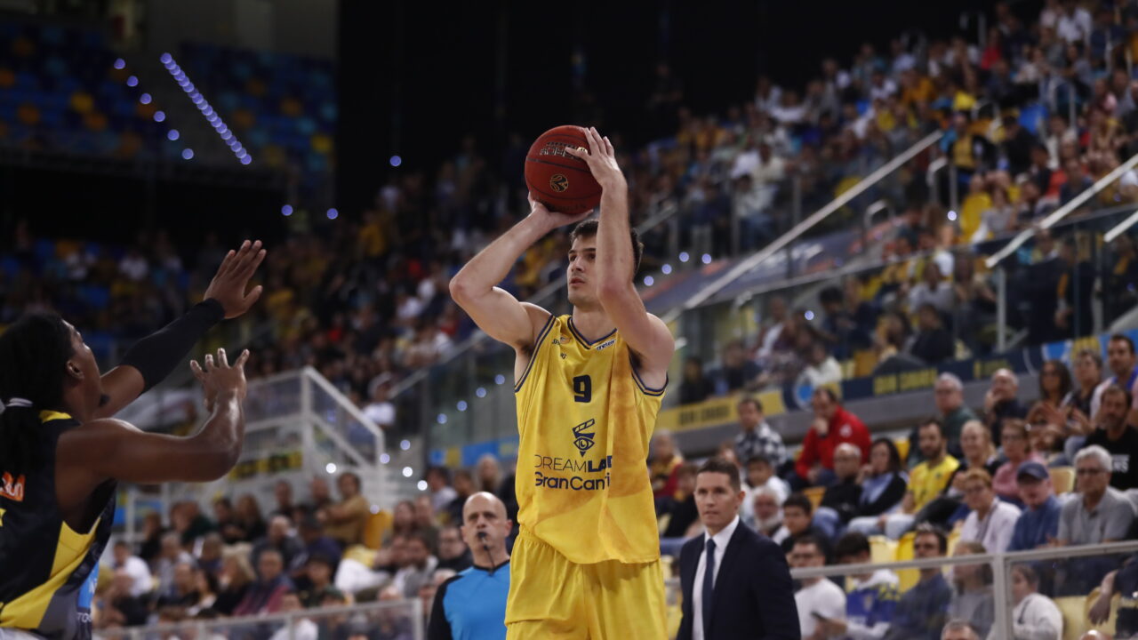 Jugador del CB Gran Canaria lanza a canasta durante un partido concurrido.