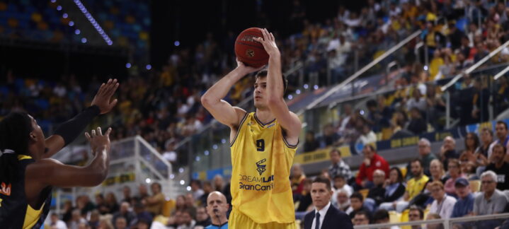 Jugador del CB Gran Canaria lanza a canasta durante un partido concurrido.