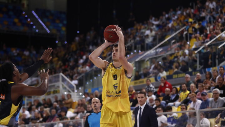 Jugador del CB Gran Canaria lanza a canasta durante un partido concurrido.