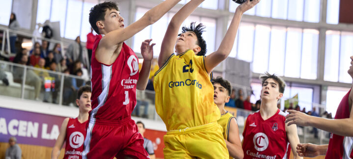Dos jugadores de baloncesto compiten por el balón en un partido infantil.