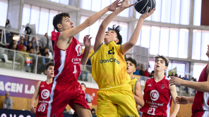 Dos jugadores de baloncesto compiten por el balón en un partido infantil.