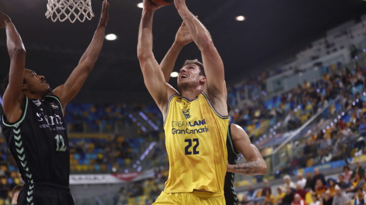 Jugadores en acción durante un partido de baloncesto, luchando por el aro.
