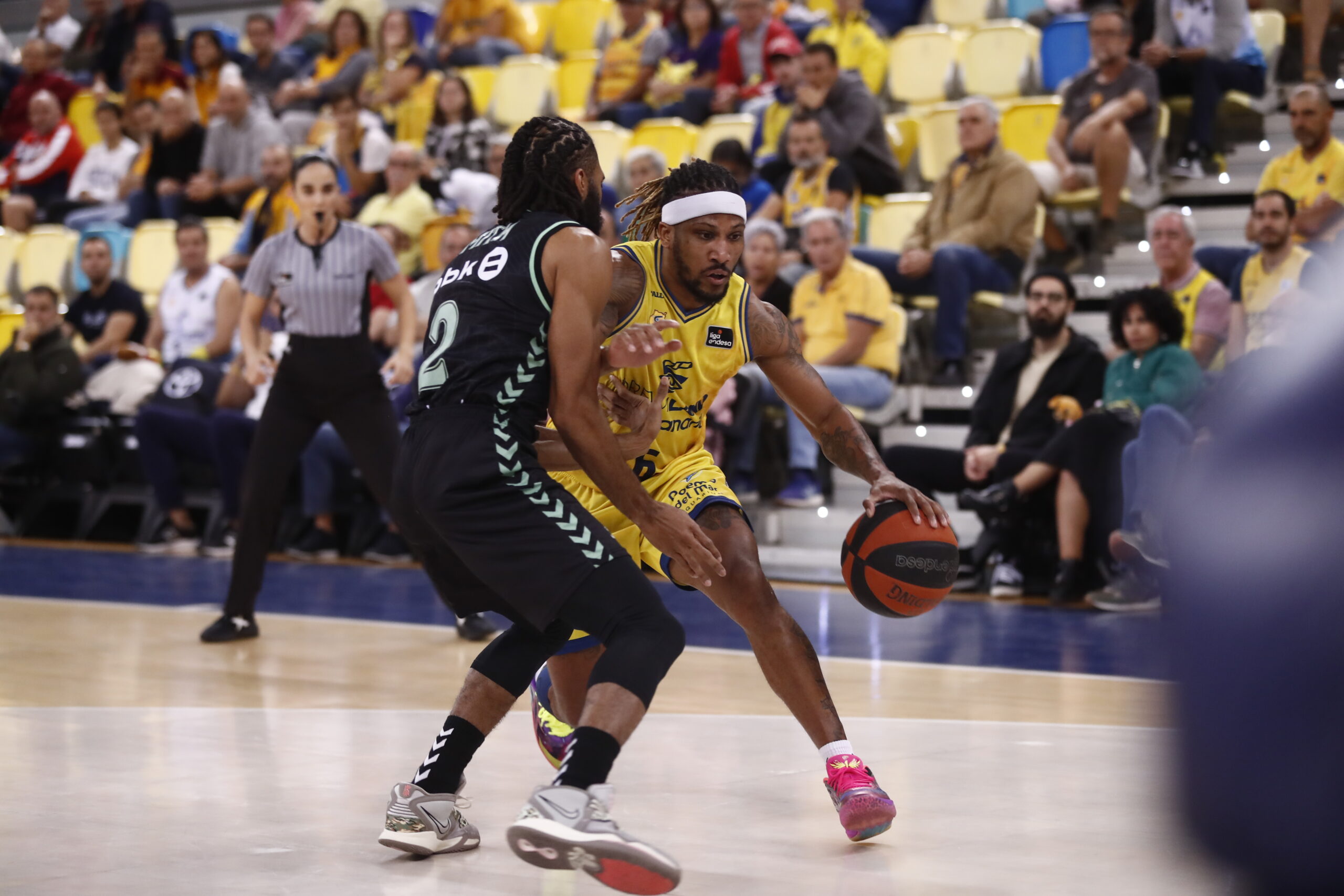 Jugador del Dreamland Gran Canaria driblando ante un rival en un partido de baloncesto.
