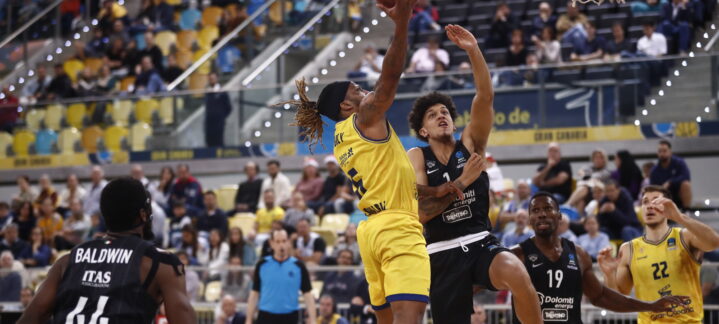 Jugador del Gran Canaria en acción, intentando encestar mientras es defendido.