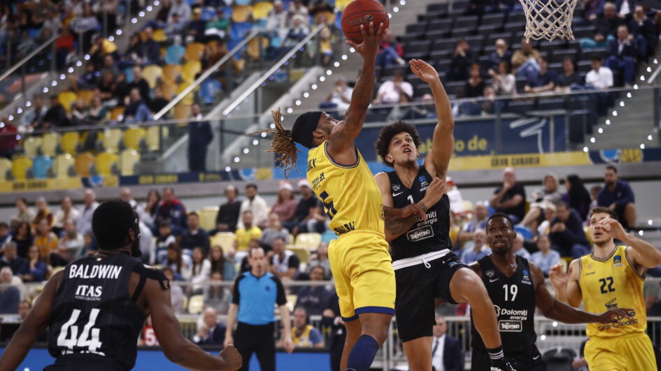 Jugador del Gran Canaria en acción, intentando encestar mientras es defendido.