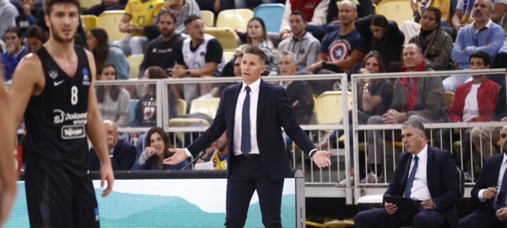 Entrenador Jaka Lakovic gesticula en un partido, mientras jugadores y público observan.