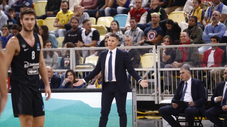 Entrenador Jaka Lakovic gesticula en un partido, mientras jugadores y público observan.