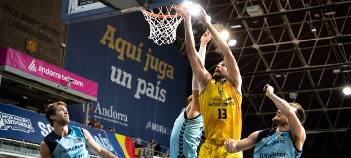 Jugadores en acción durante un partido de baloncesto, con una canasta en juego.