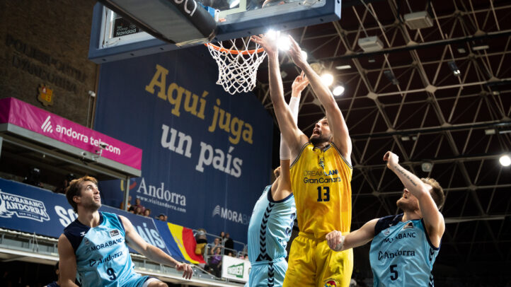 Jugadores en acción durante un partido de baloncesto, con una canasta en juego.