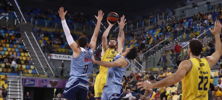 Jugadores del Gran Canaria en un salto para disputar el balón en un partido de baloncesto.