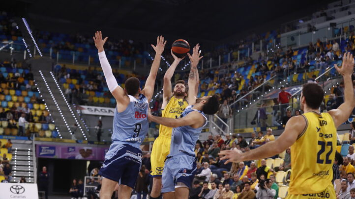 Jugadores del Gran Canaria en un salto para disputar el balón en un partido de baloncesto.