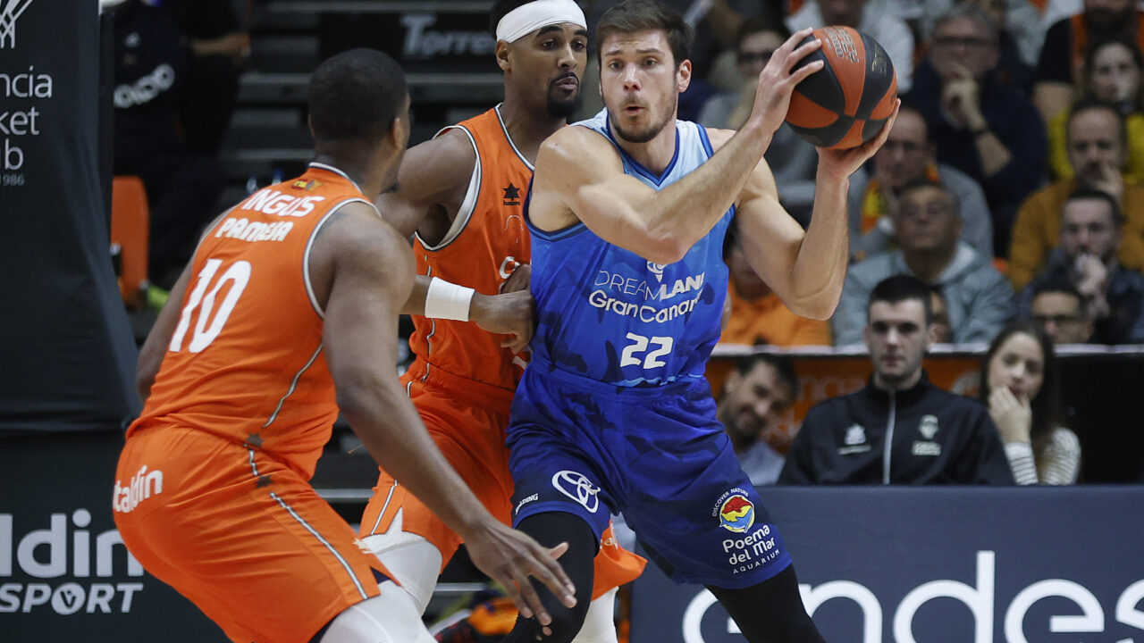 Jugador del Gran Canaria en acción, driblando con el balón ante defensores rivales.