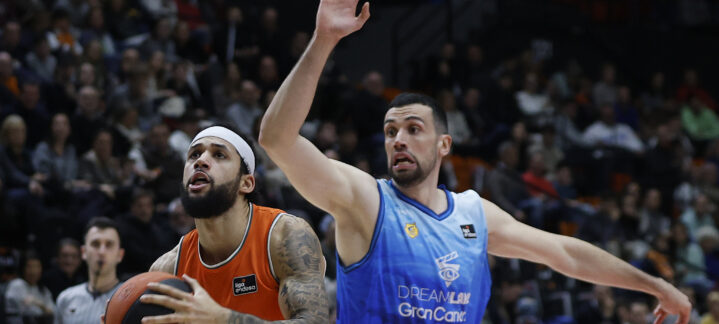 Jugadores de baloncesto en acción, uno atacando con el balón y el otro defendiendo.