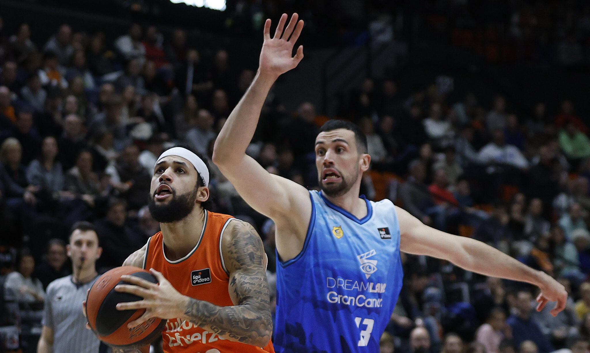 Jugadores de baloncesto en acción, uno atacando con el balón y el otro defendiendo.