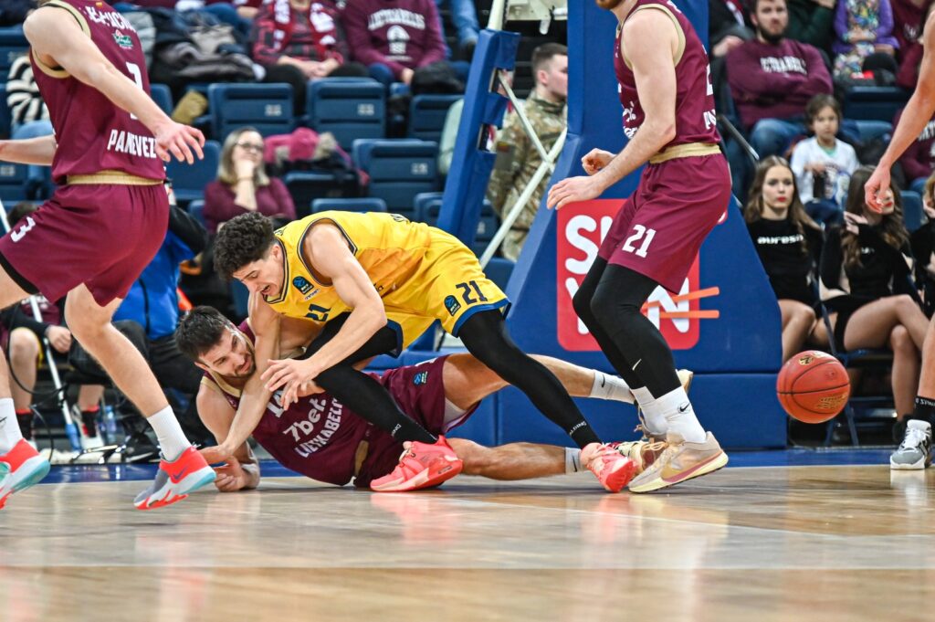 Jugadores en el suelo disputando el balón durante un partido de baloncesto.