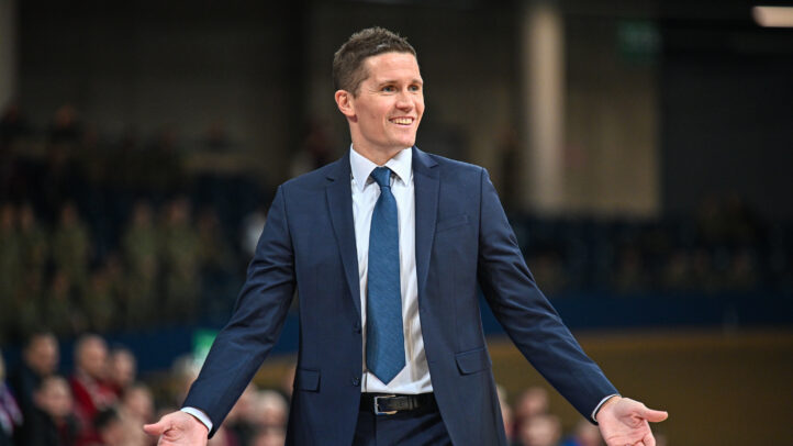 Entrenador sonriente del CB Gran Canaria durante una conferencia, con brazos abiertos.