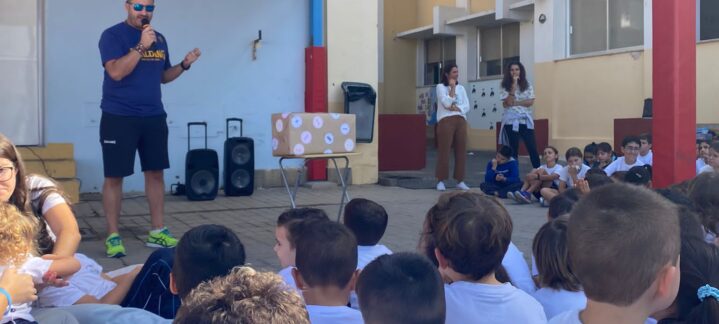 protagonista en la llegada de la Antorcha Olímpica al Colegio Príncipe de Asturias",Niños escuchando a un responsable del proyecto en un evento escolar con la antorcha olímpica.