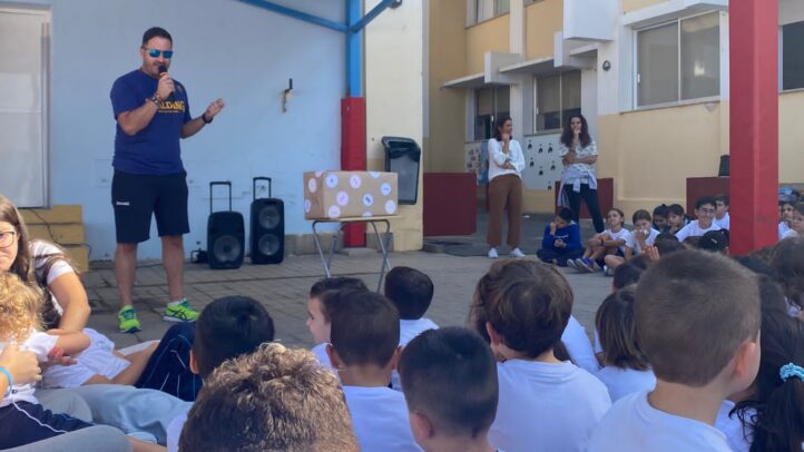 protagonista en la llegada de la Antorcha Olímpica al Colegio Príncipe de Asturias",Niños escuchando a un responsable del proyecto en un evento escolar con la antorcha olímpica.