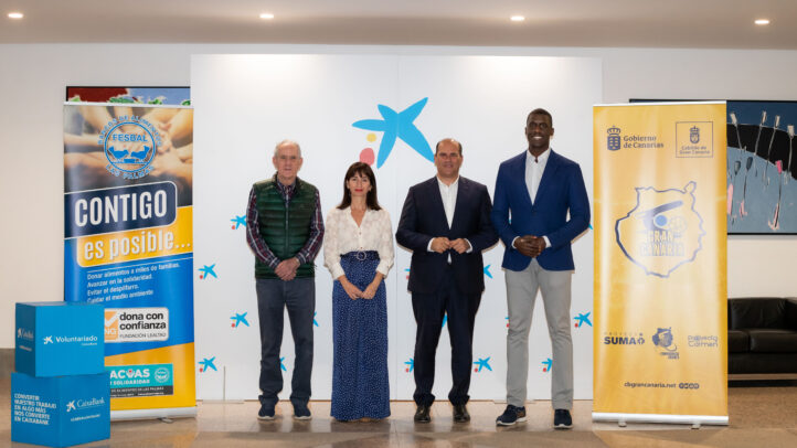 Cuatro personas posan en un evento del Club Baloncesto Gran Canaria junto a carteles de patrocinadores.