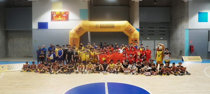 Participantes del torneo internacional de baloncesto posan con trofeos y banderas.