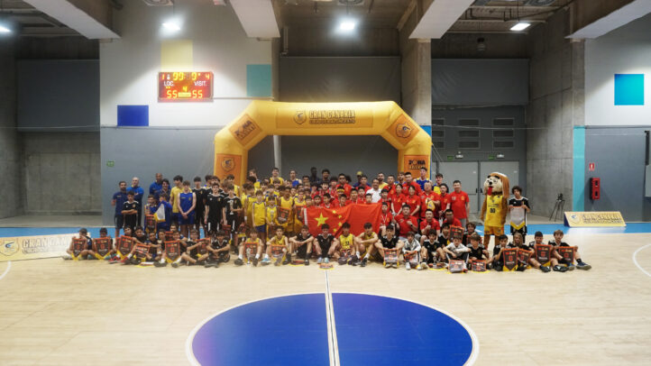 Participantes del torneo internacional de baloncesto posan con trofeos y banderas.