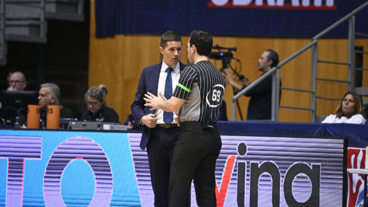 Entrenador conversando con un árbitro durante un partido de baloncesto.