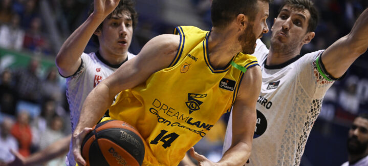 Jugador del Dreamland Gran Canaria intenta driblar entre defensores en un partido.