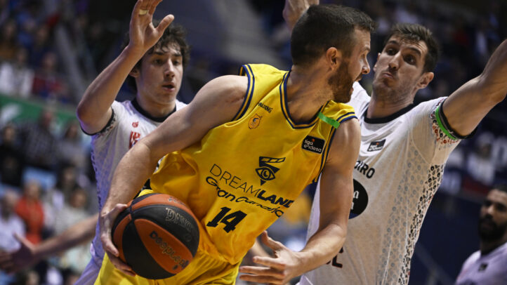Jugador del Dreamland Gran Canaria intenta driblar entre defensores en un partido.