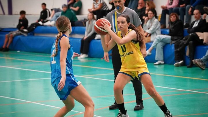 Jugadora del sénior femenino con balón, preparándose para pasar en un partido de baloncesto.